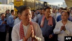 FILE - Cambodian Minister of Public Works and Transport Sun Chanthol, center left, and tycoon Kith Meng, right, chairman of The Royal Group gestures on arrival in Phnom Penh railway station on July 4, 2018.