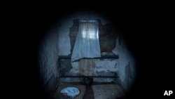 Seen through a peephole, a sheet covers the window of a jail cell in a police department in Izium, Ukraine, Sept. 22, 2022.