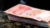 FILE - Chinese 100 yuan banknotes sit on a bank counter in Beijing, March 30, 2016. The Chinese currency has plummeted since former U.S. President Donald Trump was elected to another term on Nov. 5.