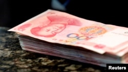 FILE - Chinese 100 yuan banknotes sit on a bank counter in Beijing, March 30, 2016. The Chinese currency has plummeted since former U.S. President Donald Trump was elected to another term on Nov. 5.