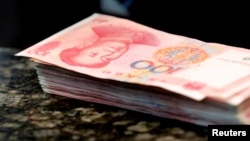 FILE - Chinese 100 yuan banknotes are seen on a counter of a branch of a commercial bank in Beijing, March 30, 2016. 