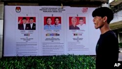 Seorang pria berjalan melewati spanduk KPU yang memperlihatkan foto-foto calon presiden di Jakarta, 22 Januari 2024. Indonesia dijadwalkan mengadakan pemilihan presiden pada 14 Februari. (AP/Dita Alangkara)