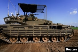 Seorang tentara Israel menunjuk ke kamera saat ia mengendarai tank di dekat perbatasan Israel-Gaza di Israel, 26 Januari 2024. (Foto: REUTERS/Alexandre Meneghini)