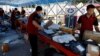 FILE - Delivery workers sort packages on a conveyor belt, ahead of a shopping festival at a logistics station in Beijing, June 12, 2023. 