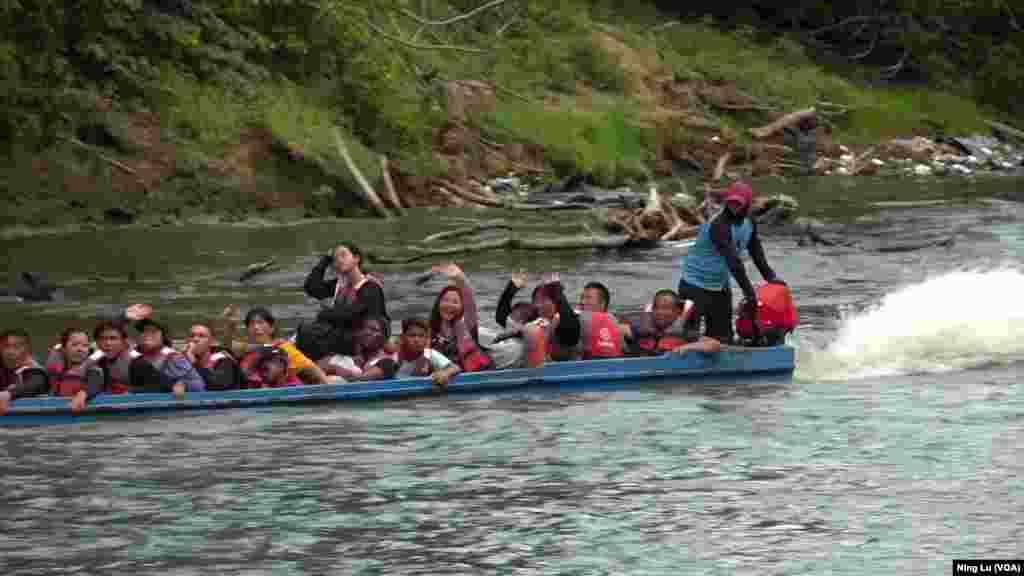 Chinese migrants on a boat wave at the camera on Feb. 24, 2024. Most had just spent a few days trekking through Panama&#39;s Darien rain forest area.