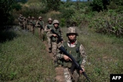 FILE - Members of the Mandalay Peoples Defense Forces patrol near the front line amid clashes with Myanmar's military in northern Shan state, Dec. 10, 2023.