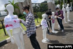 Para aktivis menyiapkan boneka peraga dalam kampanye untuk menghapuskan kekerasan terhadap perempuan di depan gedung DPR/MPR di Senayan, Jakarta, 8 Desember 2020. (Foto: Bay Ismoyo/AFP)