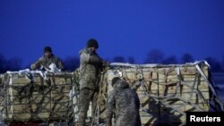 Anggota militer Ukraina membongkar kiriman bantuan militer dari AS di Bandara Internasional Boryspil di luar Kota Kyiv, pada 5 Februari 2022. (Foto: Reuters/Valentyn Ogirenko)