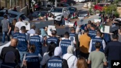 Palestinian journalists carry mock coffins of colleagues killed during the current Israel-Hamas war, during a symbolic funeral procession toward a United Nations office in the West Bank city of Ramallah, Nov. 7, 2023.