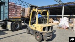 联合国和红新月会的工作人员在加沙地带一个仓库卸下准备发放给巴勒斯坦人的救济物资。（2023年10月23日）