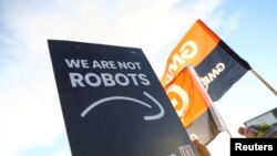 Transparent u rukama radnika Amazona na kom piše "Mi nismo roboti"