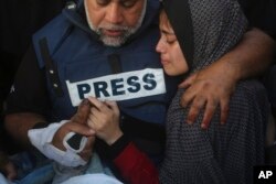 Novinar Al Džazire Vael Al-Dahduh drži ruku svoga sina Hamze, koji je takođe radio za Al Džaziru i koji je ubijen u izraelskom udaru na Rafu, u Pojasu Gaze, 7. januara 2024.