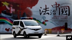 资料照：一辆警车驶过北京街头一堵宣传中国法治的宣传墙。（2016年12月28日）