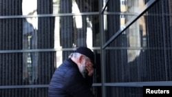 A man reacts in front of a wall bearing the names of victims during a ceremony marking International Holocaust Remembrance Day at the Holocaust Memorial Center in Budapest, Hungary, Jan, 26, 2024. 