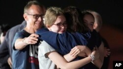 自由欧洲电台记者阿尔苏·库尔马舍娃(Alsu Kurmasheva,右二)从俄罗斯获释后,在马里兰州安德鲁斯空军基地与丈夫帕维尔·布托林(Pavel Butorin,左)以及女儿米里亚姆·布托林(Miriam Butorin)和比比·布托林(Bibi Butorin)拥抱。(2024 年 8 月 1 日)