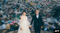Foto selebaran ini diambil pada 14 Oktober 2023 dan dirilis oleh Owen Kang pada 20 Oktober 2023 memperlihatkan Iris Hsueh (Kiri) dan tunangannya Ian Ciou di depan tumpukan sampah di Puli, Kabupaten Nantou. (Handout / OWEN KANG / AFP)