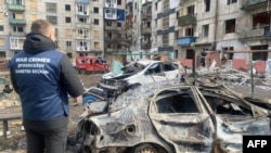 乌克兰顿涅茨克地区一栋被俄罗斯导弹摧毁的居民楼房和附近受损的汽车。（2024年3月10日）