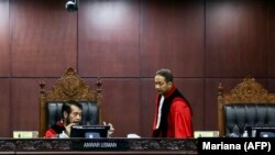 Hakim Mahkamah Konstitusi Anwar Usman (kiri) dan Suhartoyo (kanan) berbincang saat sidang memutus permohonan perubahan syarat pencalonan presiden, di Jakarta, 16 Oktober 2023. (Foto: AFP/MARIANA)