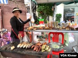 អ្នកស្រី ឆាន់ គន្ធា កំពុងអាំងត្រី ដើម្បីទុកលក់ នៅទល់មុខផ្សារកាប់ ក្នុងខណ្ឌចំការមន រាជធានីភ្នំពេញ កាលពីថ្ងៃទី២ ខែវិច្ឆិកា ឆ្នាំ២០២៣។ (លាស់ លីបលីប/វីអូអេ)