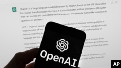 FILE - The OpenAI logo is seen on a mobile phone in front of a computer screen displaying output from ChatGPT. Experts say artificial intelligence will make investigative journalism easier, especially for smaller newsrooms.