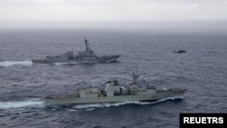 资料照片：美国海军导弹驱逐舰“钟云号”与加拿大皇家海军护卫舰“蒙特利尔号”在南中国海进行演习期间并肩航行。（2023年5月30日）