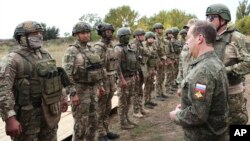 FILE - Russian Security Council Deputy Chairman Dmitry Medvedev, front right, speaks to Russian military members during his visit at a military training range in the Russian-controlled Donetsk region, Ukraine, Sept. 15, 2023. (Pool Sputnik via AP)
