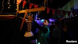 Seorang pria Palestina menggantungkan lentera di tenda pengungsian untuk menyambut datangnya Ramadan, di tengah konflik Israel-Hamas, di Rafah, di selatan Jalur Gaza, 9 Maret 2024. (Foto: REUTERS/Mohammed Salem)