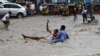 FILE - A man attempts to rescue a boy from raging floodwaters following heavy rains in Mogadishu, Somalia, Nov. 9, 2023. Farah Omar Nur, the secretary general of the Federation of Somali Journalists, says environmental journalism is not easy, especially in Somalia.