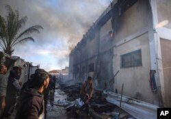 Warga Palestina mencoba memadamkan api di gedung pusat pelatihan kejuruan UNRWA yang digunakan para pengungsi sebagai tempat berlindung, setelah menjadi sasaran tank Israel di Khan Younis, Jalur Gaza selatan, 24 Januari 2024. (Foto: AP)