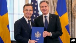 Secretary of State Antony Blinken, right, poses for a photo with Swedish Prime Minister Ulf Kristersson holding Sweden's NATO Instruments of Accession in the Benjamin Franklin Room at the State Department, in Washington, March 7, 2024.