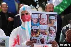 A protester wearing a shroud holds a placard during a protest in solidarity with Gaza and Palestinian prisoners in the Israeli jails, Hebron, in the Israeli-occupied West Bank, Nov.14, 2023.
