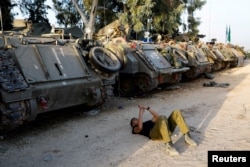 An Israeli soldier lies next to armoured personnel carriers (APC), amid the ongoing conflict between Israel and the Palestinian group Hamas, near Israel's border with Gaza in southern Israel, Nov. 23, 2023.
