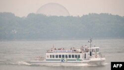 Sebuah kapal wisata melintas di sungai St-Lawrence di Montreal, Quebec, Kanada, di tengah asap yang disebabkan oleh kebakaran hutan di Quebec Utara, 25 Juni 2023. (ANDREJ IVANOV / AFP)