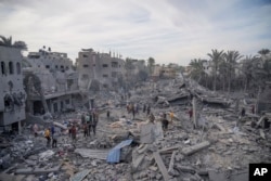Palestinians look at destruction by the Israeli bombardment of the Gaza Strip, in Deir al Balah, Nov. 22, 2023.