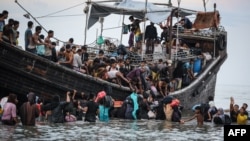 Pengungsi Rohingya yang baru tiba kembali ke perahu setelah masyarakat setempat memutuskan untuk mengizinkan mereka mendarat sementara untuk mendapatkan air dan makanan di Ulee Madon, provinsi Aceh, 16 November 2023. (Amanda Jufrian / AFP)