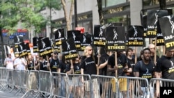 资料照片:美国影视演员协会(SAG-AFTRA)2023年7月17日在纽约洛克菲勒中心的全国广播公司(NBC)外举着标语游行。 (美联社图片)