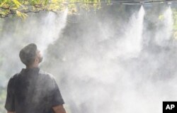 Arhiva - Čovek se rashlađuje u vodenoj izmaglici u Montrealu, 6. septembra 2023.