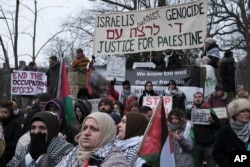 Para pengunjuk rasa memegang tanda dan mengibarkan bendera Palestina dalam aksi demo di luar Mahkamah Internasional di Den Haag, Belanda, Kamis, 11 Januari 2024. (AP/Patrick Post)