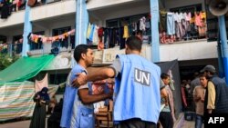 Para pekerja Badan Bantuan dan Pekerjaan PBB untuk Pengungsi Palestina (UNRWA) di taman bermain sekolah yang dikelola UNRWA yang diubah menjadi tempat penampungan bagi pengungsi Palestina di Khan Younis di Jalur Gaza selatan, 25 Oktober 2023 .(Foto: AFP)