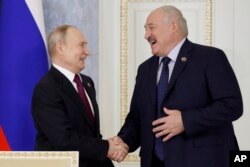Presiden Rusia Vladimir Putin, kiri, dan Presiden Belarusia Alexander Lukashenko berjabat tangan saat pertemuan Dewan Tertinggi Negara Persatuan di St. Petersburg, Rusia, 29 Januari 2024. (Foto: via AP)