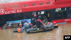 Petugas penyelamat Korea Selatan mencari orang hilang di dekat sebuah bus di sepanjang jalanan yang tergenang banjir pasca hujan lebat di kota Cheongju, Minggu 16 Juli 2023.
