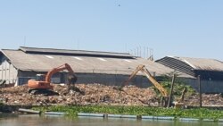 Dua eskavator memindahkan tumpukan sampah yang ada di pinggir sungai Surabaya wilayah Gunungsari, Surabaya, setelah terjaring pipa yang dipasang. (Foto: VOA/Petrus Riski)