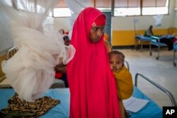 FILE - A woman holds a child at a clinic in Dollow, Somalia, Sept. 21, 2022.