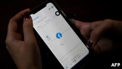 A woman uses her mobile phone to check Facebook in Yangon, Feb. 4, 2021, as Myanmar's generals ordered internet providers to restrict access to Facebook, days after they seized power. 