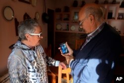 Orang tua Santiago Sanchez Cogedor, Celia Cogedor (kiri) dan Santiago Sanchez menunjukkan foto putra mereka melalui telepon genggam mereka, di kediaman mereka di Henches, Spanyol, Senin, 24 Oktober 2022. (AP/Paul White)