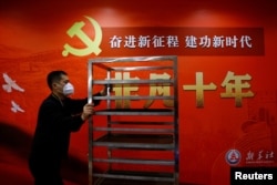 一名工作人员在北京一家酒店的中共二十大新闻中心走过宣传中国领导人习近平的标语。（2022年10月19日）