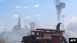 Petugas pemadam kebakaran Ukraina berusaha memadamkan api pada kapal yang terbakar di pelabuhan Odesa, Ukraina, setelah serangan misil menghantam area pelabuhan pada 23 Juli 2022. (Foto: Odessa City Council/AFP)