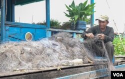 Sout To cleans up the gill nets in front of his floating house in Peam Bang village of Kampong Thom province, on May 04, 2022. (Khan Sokummono/VOA Khmer)
