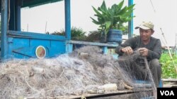 លោក សួត តូ កំពុងសម្អាត​ និង​ស្រាយ​សំណាញ់​ត្រី ដែល​ជាប់​ទៅ​ដោយ​​ស្លឹកឈើ និង​មែកឈើ​។ លោករស់នៅ​លើ​​​​​​ផ្ទៃ​ទឹក​បឹង​​ទន្លេសាប ​នៅក្នុង​ភូមិ​ពាមបាង នៃ​ខេត្តកំពង់ធំ នៅថ្ងៃទី០៤ ខែឧសភា ឆ្នាំ២០២២។ (ខាន់ សុគុំមនោ/វីអូអេ)