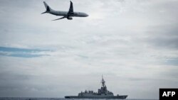 FILE - A Royal Australian Air Force P-8A Poseidon aircraft making a low pass over Royal Australian Navy destroyer HMAS Hobart during Fleet Certification Period, Feb. 24, 2022